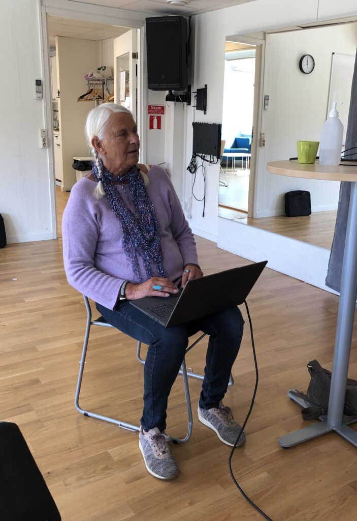 En person sitter på en stol med en laptop i knät.